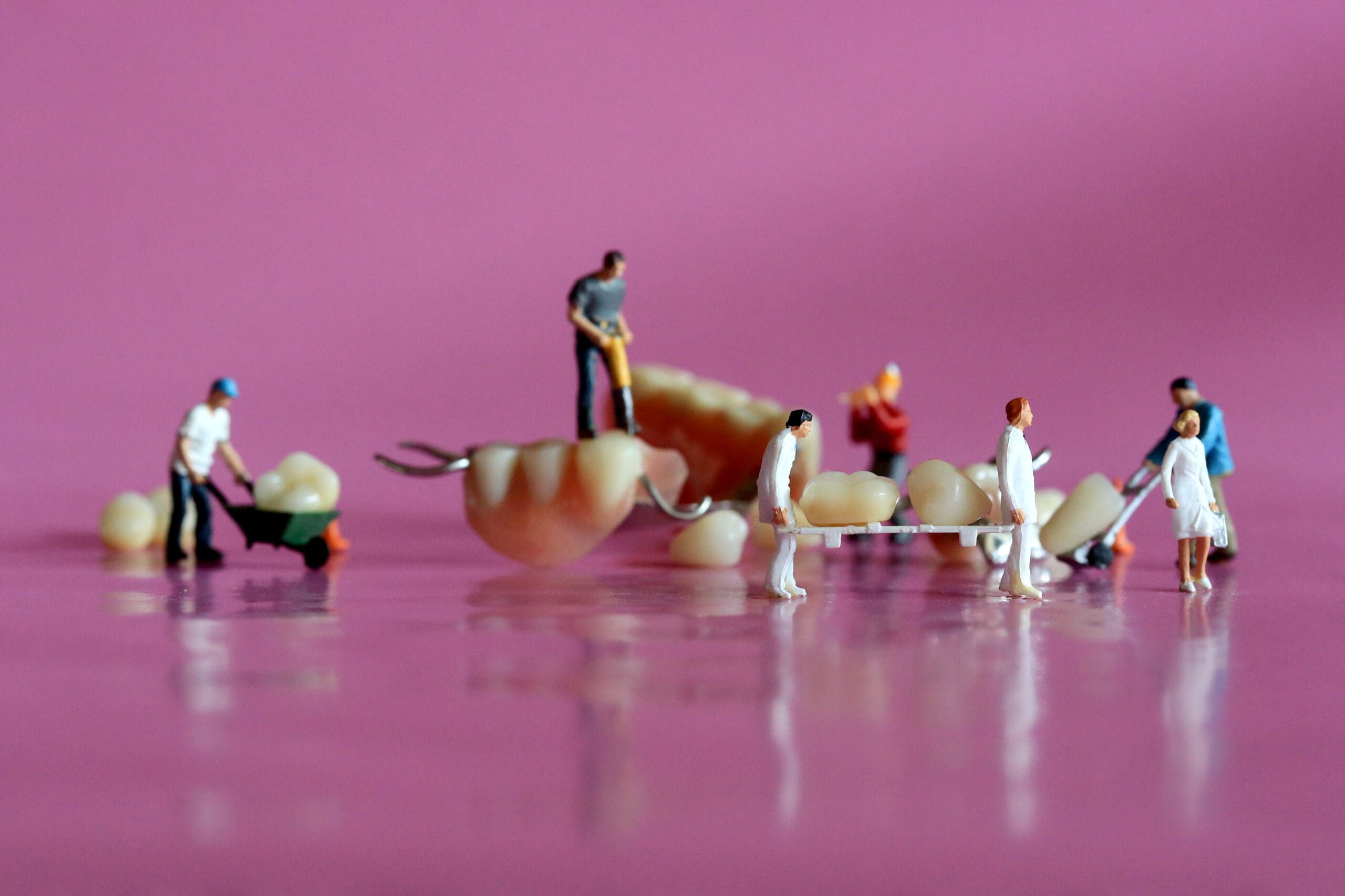 Miniature figurines on a pink background showcasing general dentistry.