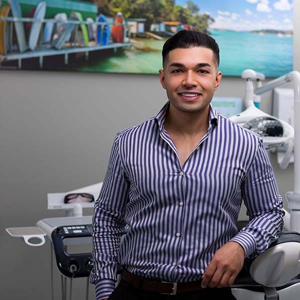 A man showcasing Invisalign clear aligners in front of a dental chair.