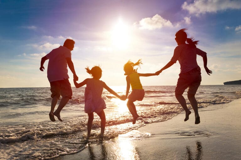 A family enjoying a fun-filled day at the beach, jumping in the air with sheer joy.